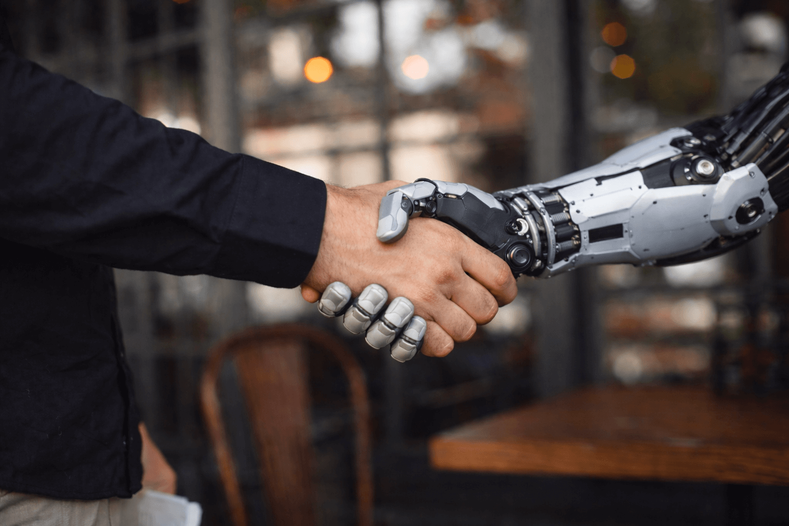 Rokovanje med človekom in robotsko roko kot simbol sodelovanja med človekom in umetno inteligenco.